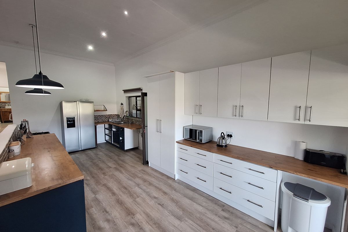 Modern kitchen featuring white cabinetry, warm wooden countertops, laminate flooring, and recessed lighting, offering a clean and functional workspace.