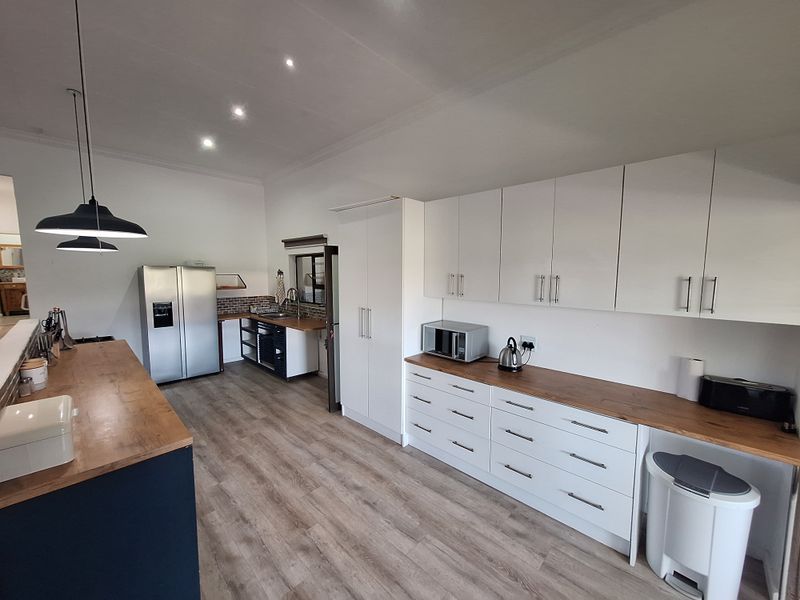 Modern kitchen featuring white cabinetry, warm wooden countertops, laminate flooring, and recessed lighting, offering a clean and functional workspace.