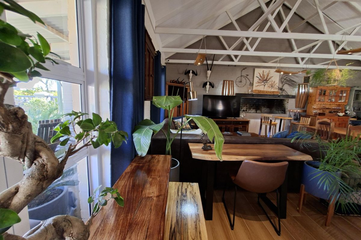 Spacious living area featuring high vaulted ceilings with exposed white trusses, tiled flooring, and a cozy fireplace, creating a warm and inviting atmosphere.