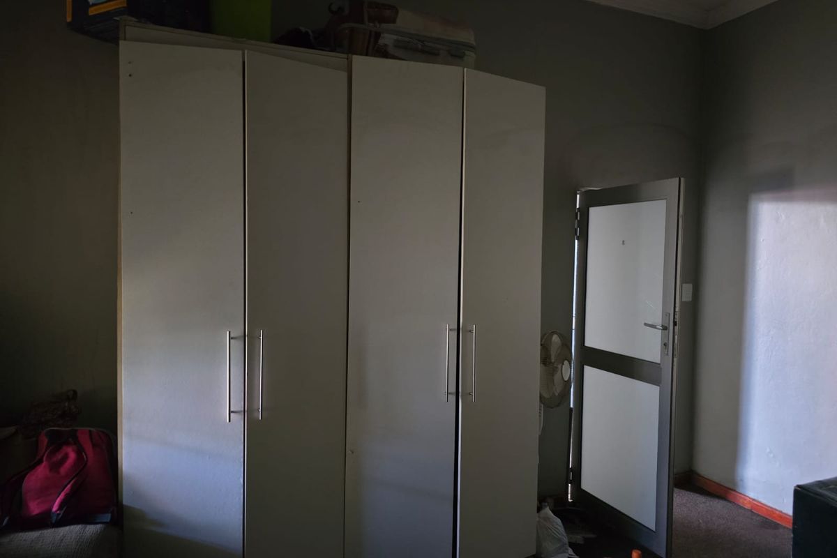 A bedroom featuring a large built-in wardrobe and an external aluminium door, providing direct access to the exterior.