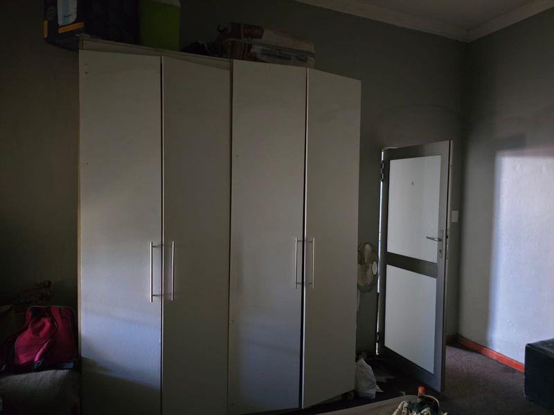 A bedroom featuring a large built-in wardrobe and an external aluminium door, providing direct access to the exterior.