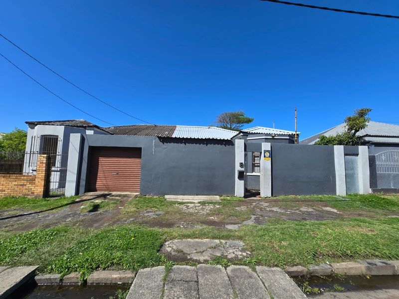 Front elevation of a residential property featuring a perimeter wall, roller garage door, and pedestrian entrance gate.