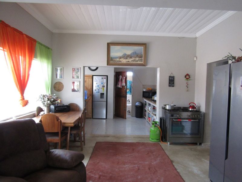 Open plan living and dining area featuring a kitchen nook with built-in shelving and a freestanding gas stove.