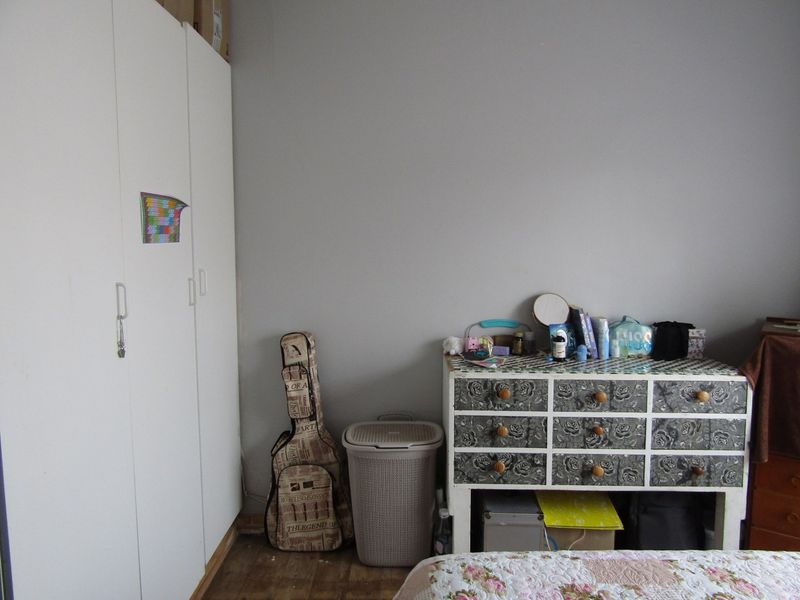 A bedroom featuring a white built-in wardrobe and neutral wall finishes, providing a functional space for storage and rest.