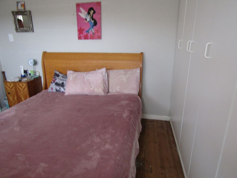 A bedroom featuring hardwood flooring and built-in white cupboards, providing functional storage space.