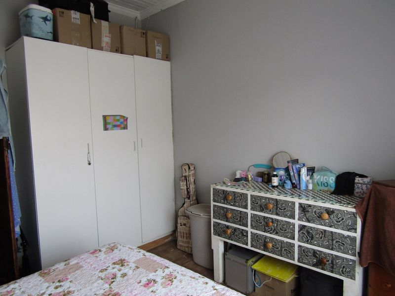 A bedroom featuring a white built-in wardrobe with ample storage space.
