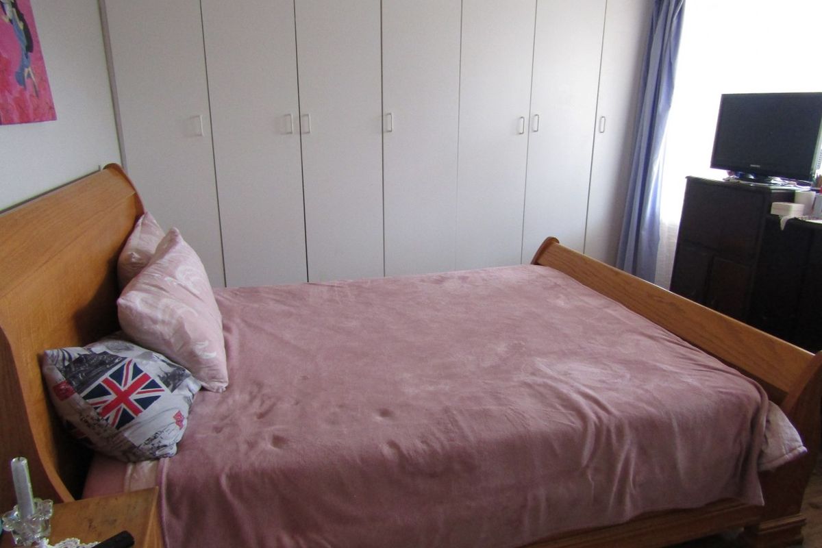 A functional bedroom featuring extensive floor-to-ceiling built-in cupboards providing ample storage space.