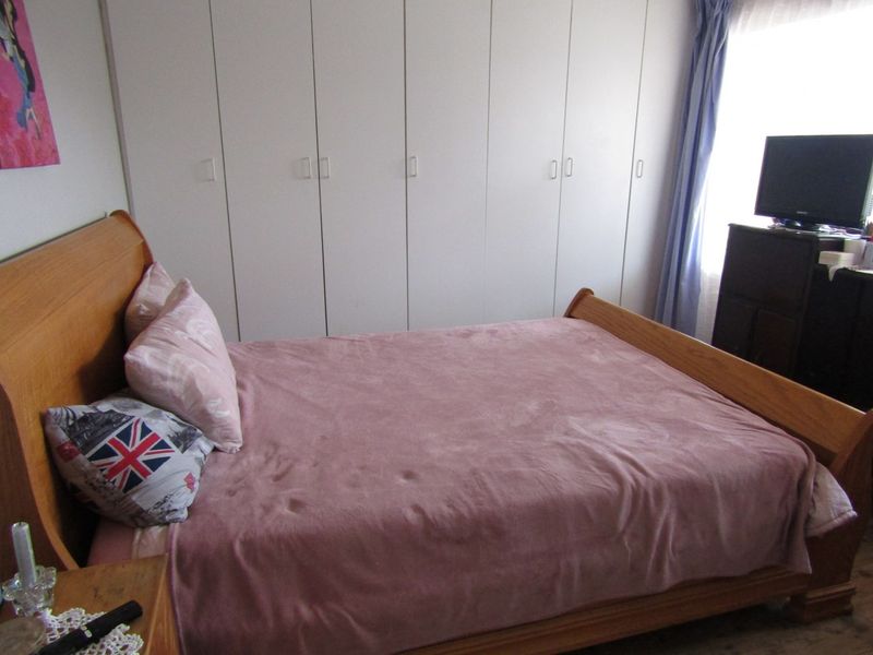 A functional bedroom featuring extensive floor-to-ceiling built-in cupboards providing ample storage space.