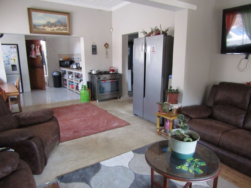 Open plan living and kitchen area featuring tiled flooring, gas stove, and integrated storage space, offering a functional layout with potential for modernization.