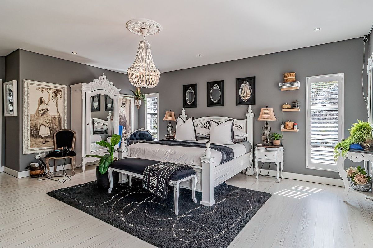 Spacious bedroom featuring light-toned laminate flooring, recessed downlighting, decorative ceiling rose, and plantation shutters providing natural light control.