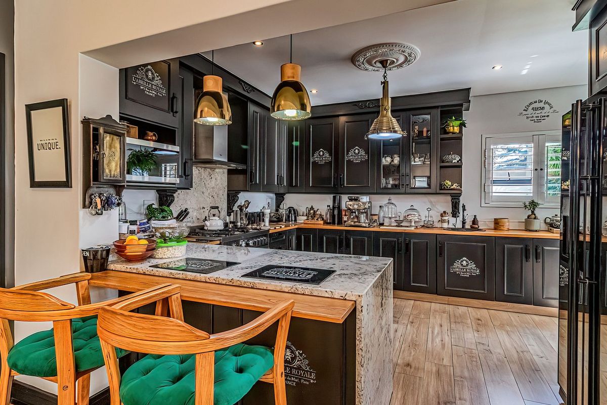A well-appointed kitchen featuring dark cabinetry, granite countertops, a central island with breakfast bar, and high-quality integrated fixtures and lighting.
