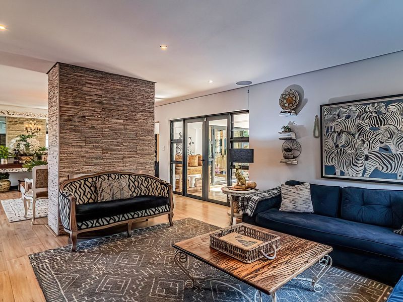 Spacious living area featuring a striking stacked stone accent wall, modern laminate flooring, and large aluminium-framed glass doors leading to the exterior.