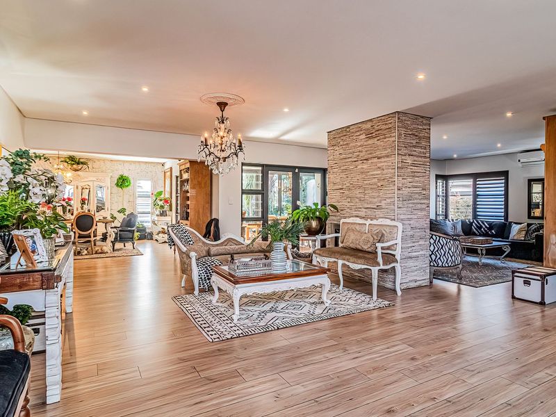 Spacious open-plan living area featuring high-quality laminate flooring, a striking stone-clad feature pillar, and elegant recessed lighting throughout the expansive interior space.