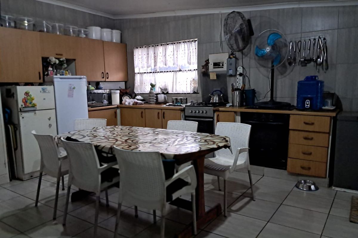 A functional kitchen featuring built-in wooden cabinetry, tiled walls and flooring, and a built-in stove and oven combination.