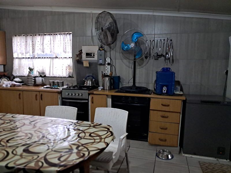A functional kitchen featuring built-in cabinetry, a gas stove, and oven, with tiled walls and flooring throughout.