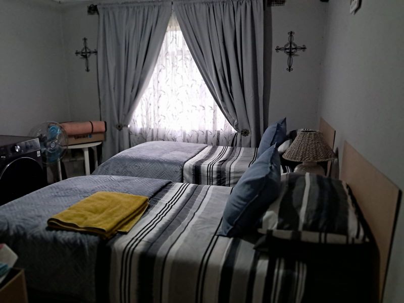 A bedroom featuring twin beds and window treatments, requiring improved lighting and staging to enhance its appeal.