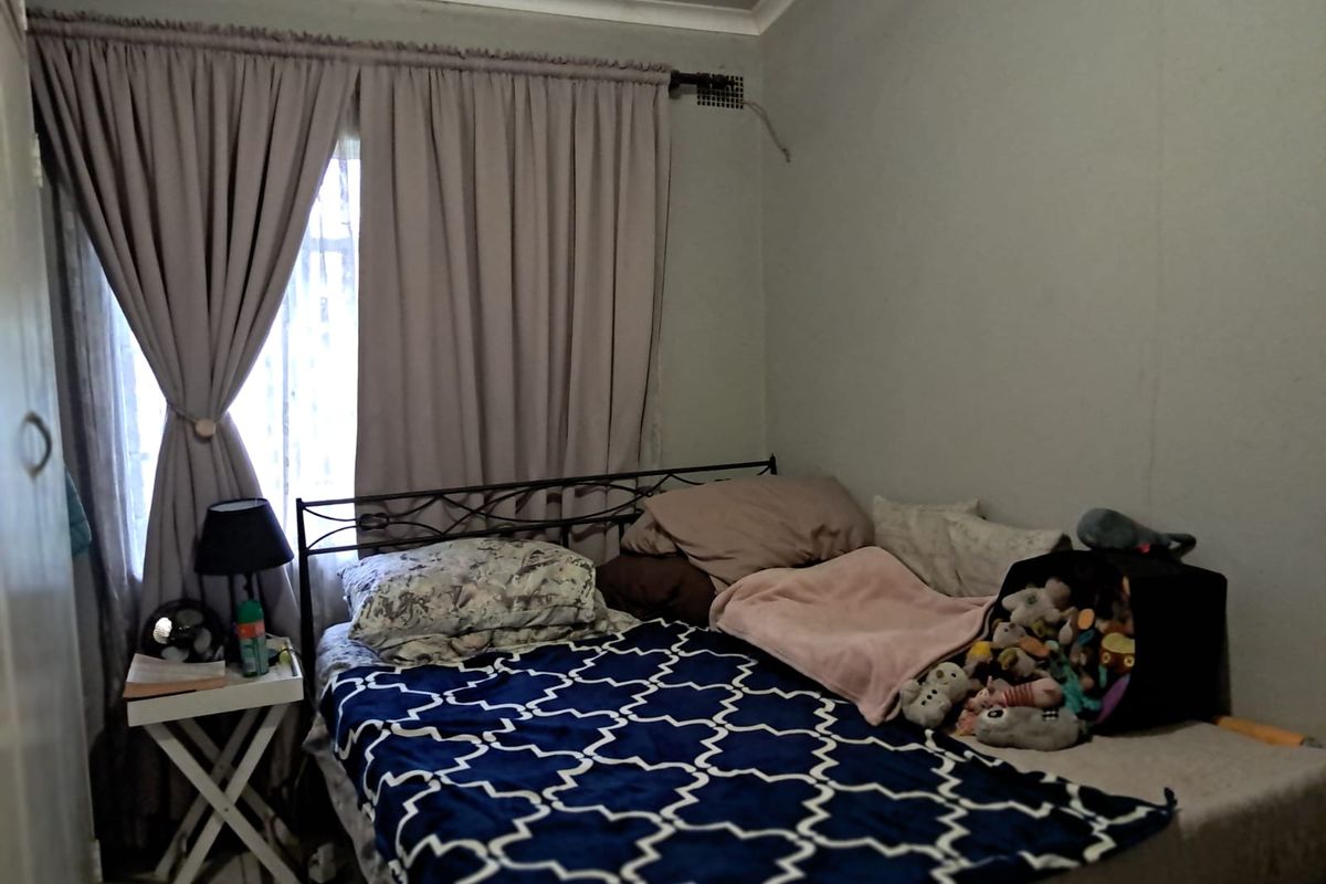 A standard bedroom featuring neutral wall finishes, cove cornicing, and a window fitted with a curtain rail.