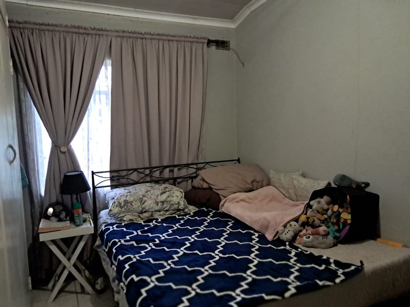 A standard bedroom featuring neutral wall finishes, cove cornicing, and a window fitted with a curtain rail.