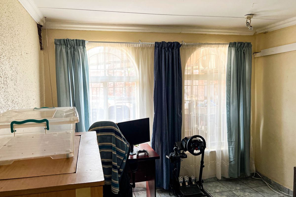 A living area featuring arched windows, tiled flooring, and ceiling coving, currently used as a multi-purpose space.