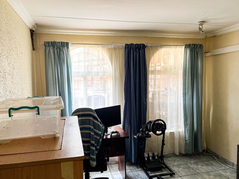 A living area featuring arched windows, tiled flooring, and ceiling coving, currently used as a multi-purpose space.