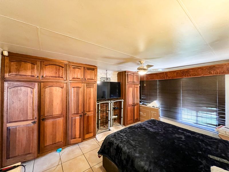 Bedroom featuring extensive built-in wooden cabinetry, tiled flooring, and an exposed brick wall section, offering ample storage space.