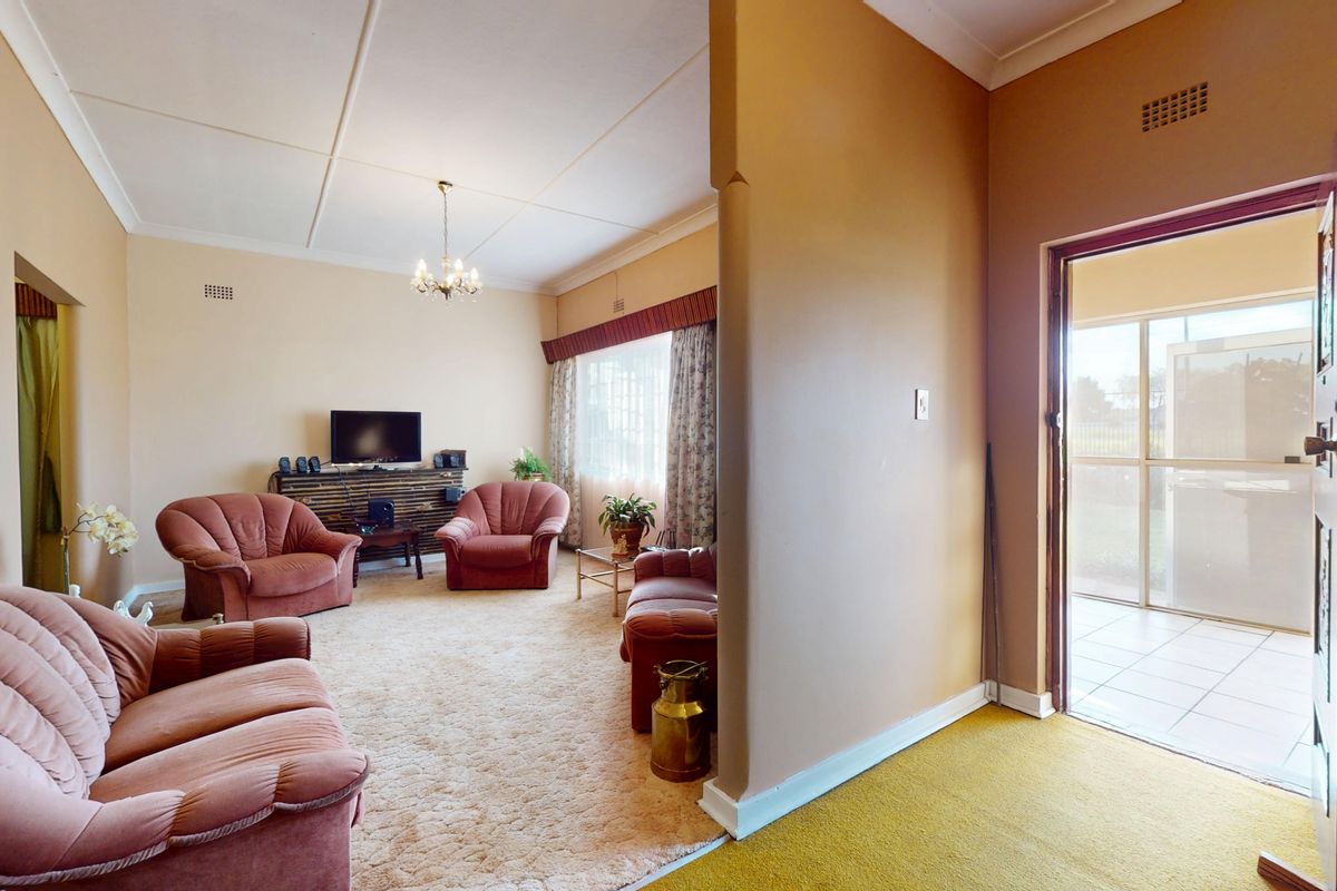 A spacious living room featuring carpeted flooring, a tiled entryway, and direct access to an outdoor patio area through a sliding glass door.
