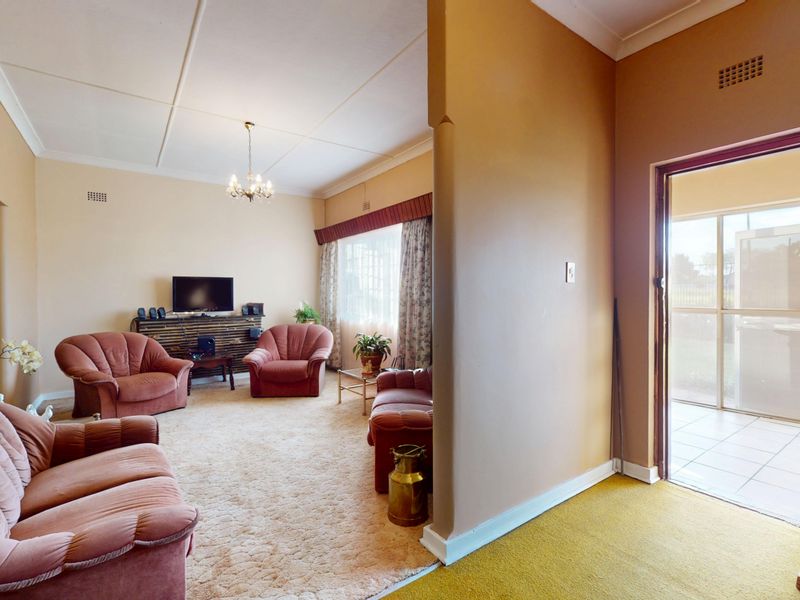 A spacious living room featuring carpeted flooring, a tiled entryway, and direct access to an outdoor patio area through a sliding glass door.