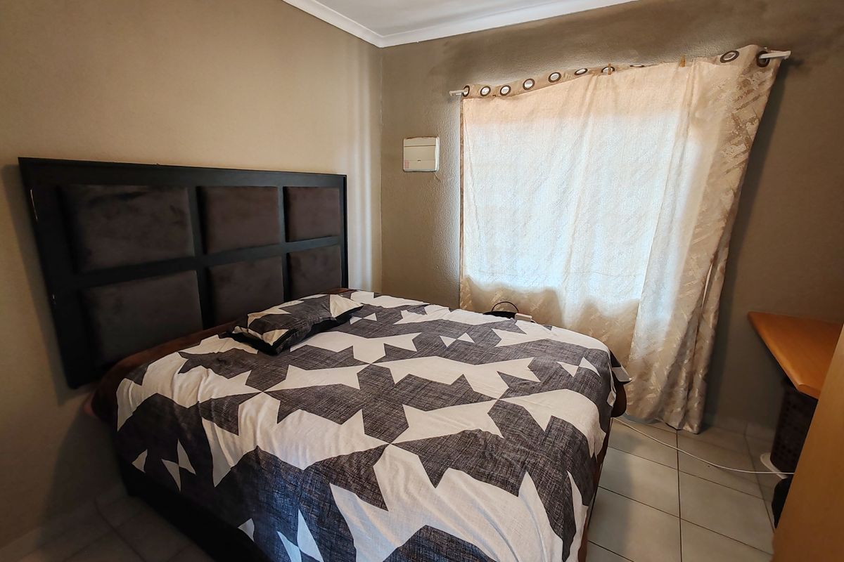A bedroom featuring tiled flooring and a built-in desk, showing signs of wall staining and wear that would benefit from cosmetic updates.