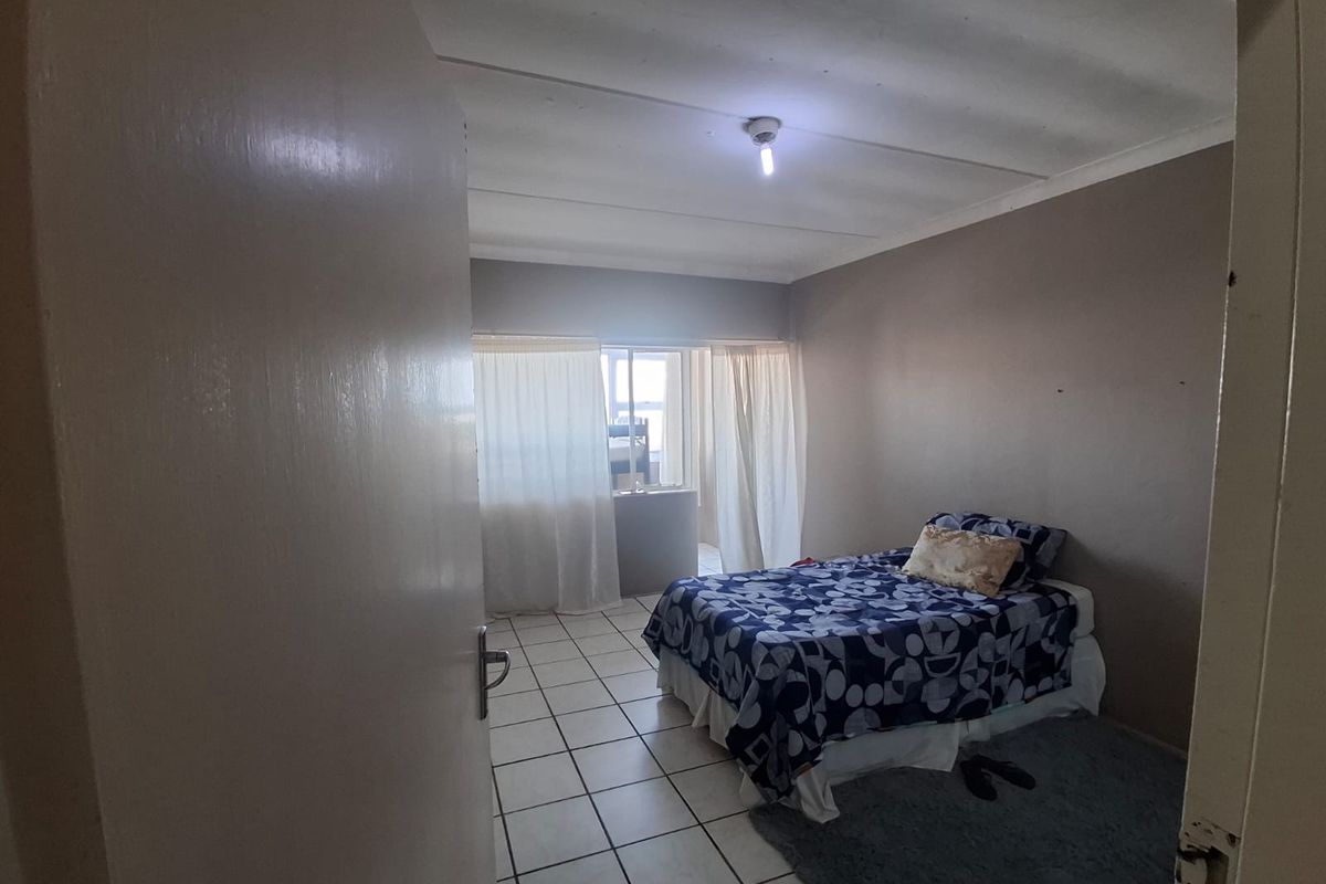 A bedroom featuring tiled flooring and neutral wall tones, offering a functional space with natural light access through the window.