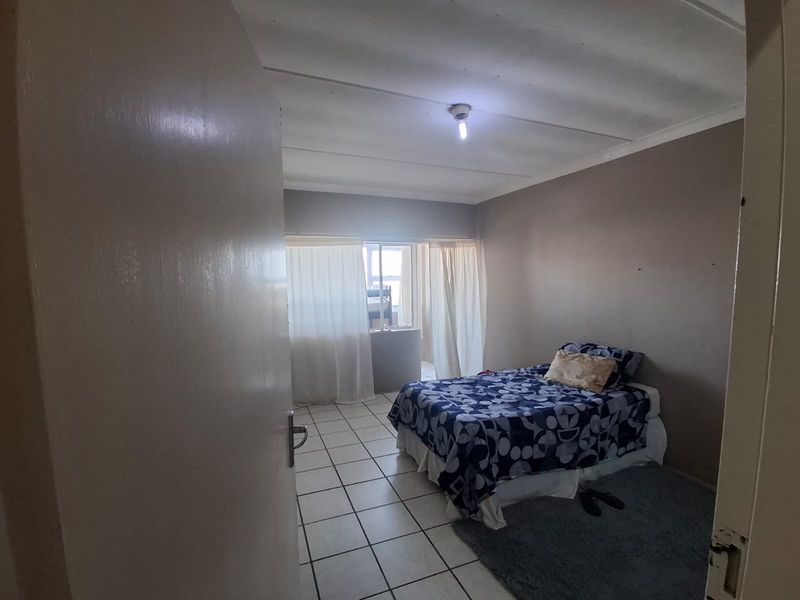 A bedroom featuring tiled flooring and neutral wall tones, offering a functional space with natural light access through the window.