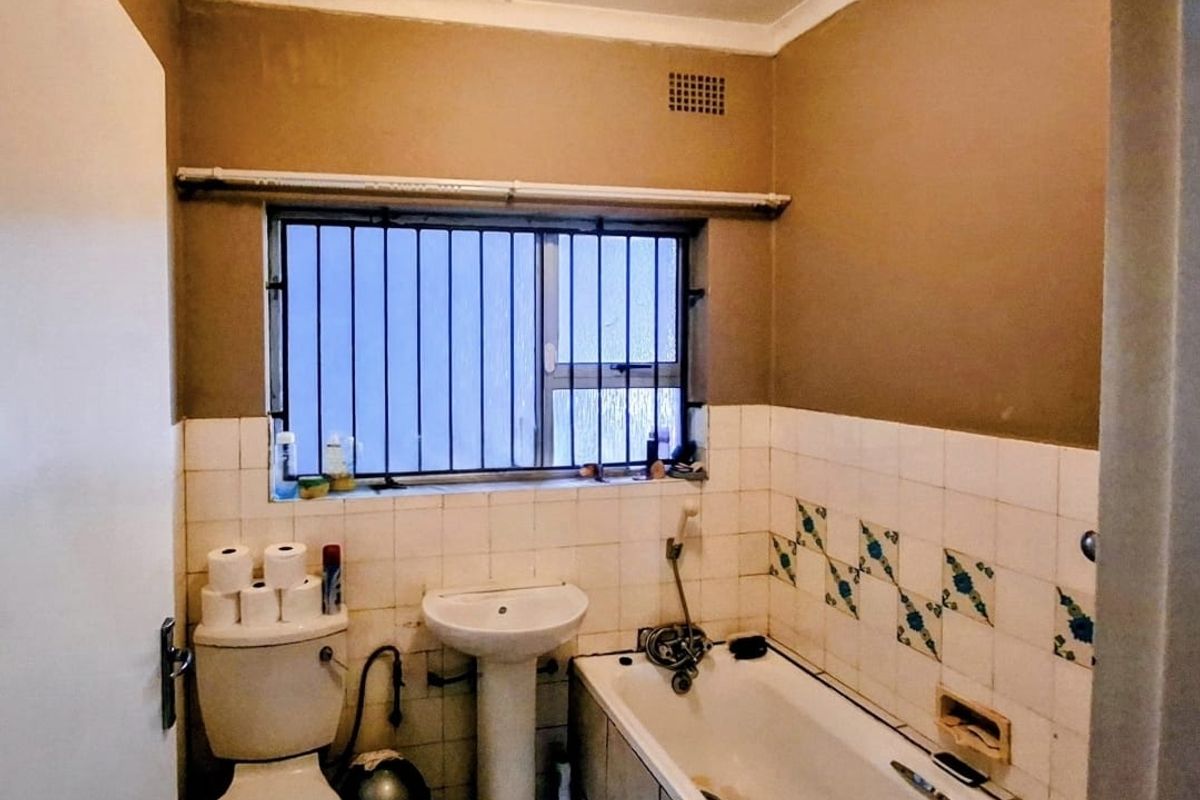 A dated bathroom featuring a pedestal basin, bathtub, and toilet, with significant potential for modernization through updated fixtures and tiling.