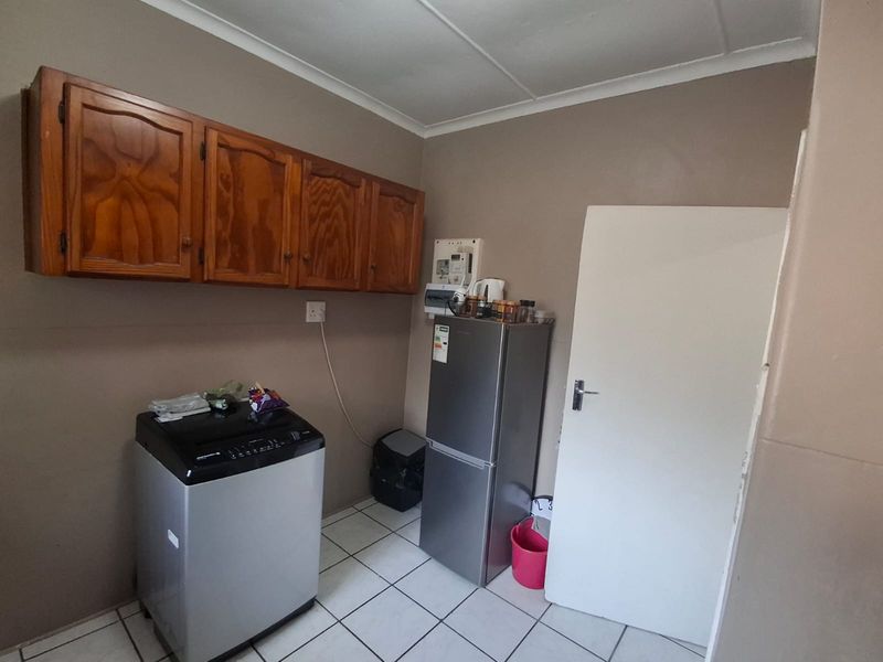 A functional laundry area featuring tiled flooring and wall-mounted wooden cabinetry, providing practical storage space for utility needs.