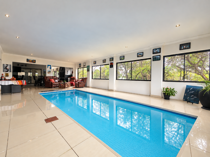 Spacious indoor swimming pool area featuring large windows, tiled flooring, and recessed lighting, creating a bright and functional entertainment space.