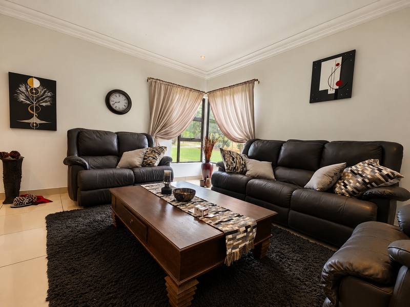 A well-maintained living room featuring tiled flooring, coved ceilings, and a corner window that provides natural light.