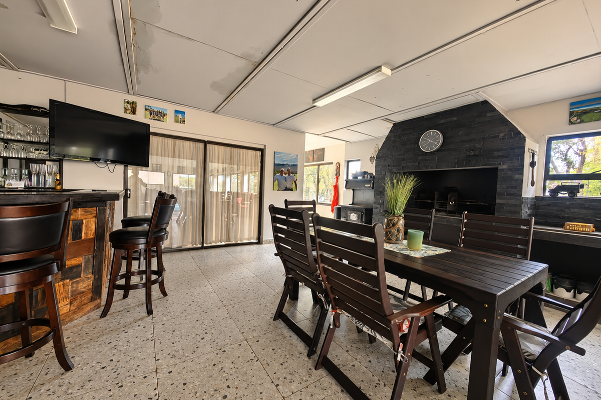 Spacious living and entertainment area featuring a built-in fireplace with stone cladding, a custom bar counter, and terrazzo flooring with access to the outdoors.