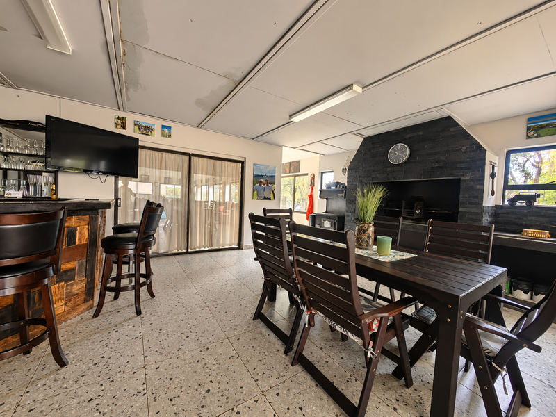 Spacious living and entertainment area featuring a built-in fireplace with stone cladding, a custom bar counter, and terrazzo flooring with access to the outdoors.