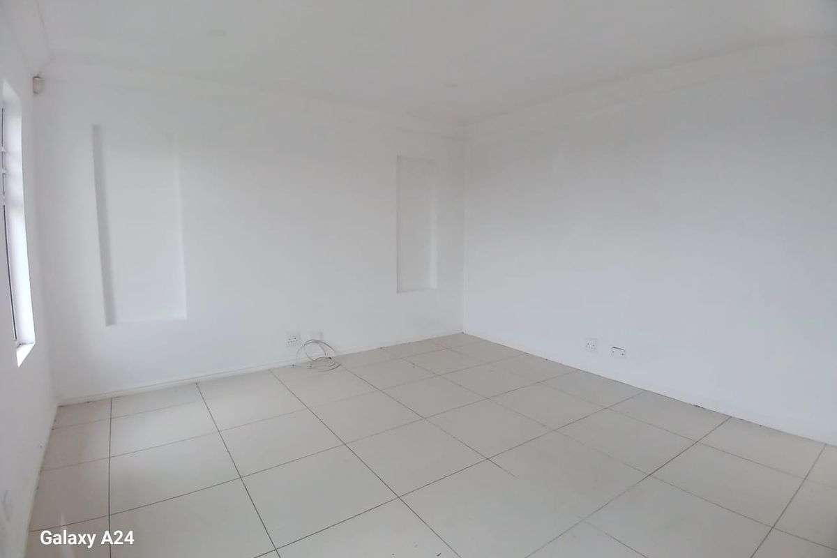 A bright, empty living area featuring neutral tiled flooring and built-in wall niches, providing a clean canvas for interior design.