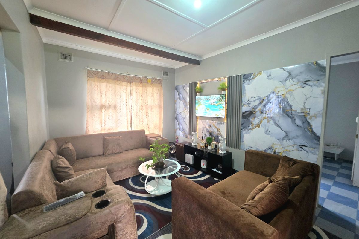 A living room featuring decorative marble-effect wall paneling, a recessed ceiling design with an exposed beam, and neutral wall finishes.