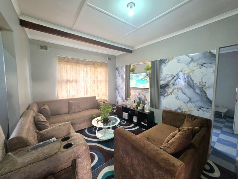 A living room featuring decorative marble-effect wall paneling, a recessed ceiling design with an exposed beam, and neutral wall finishes.