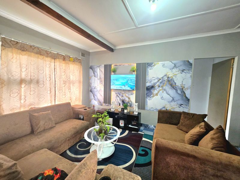 A cozy living room featuring decorative marble-effect wall paneling with integrated accent lighting and an exposed ceiling beam.