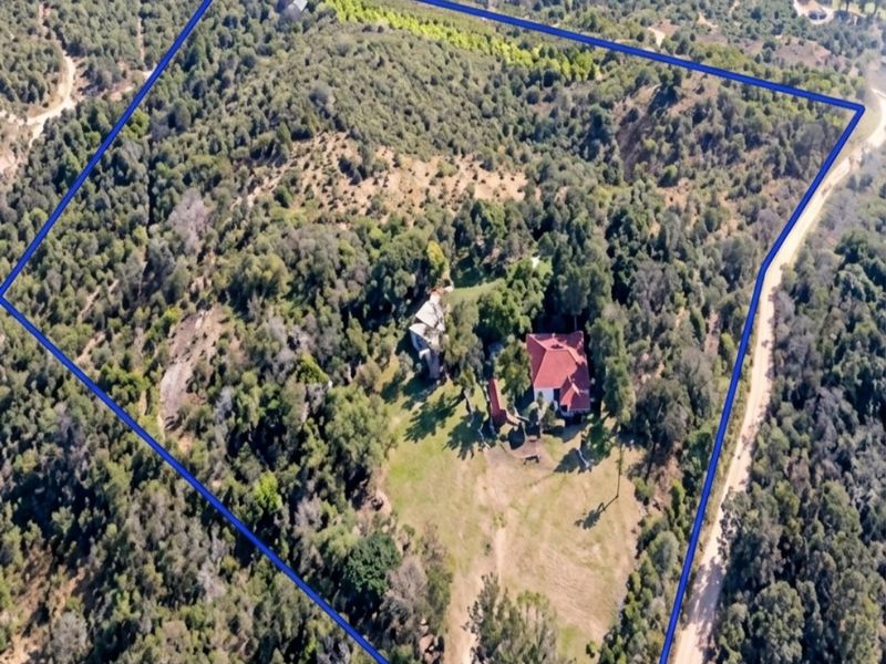 Aerial view of a large rural small holding featuring extensive wooded terrain and a main dwelling structure.