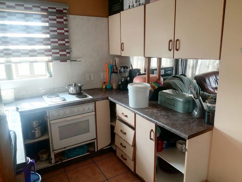 A compact kitchen featuring built-in cabinetry, laminate countertops, and an integrated electric oven and hob, requiring cosmetic updates to improve its overall condition.