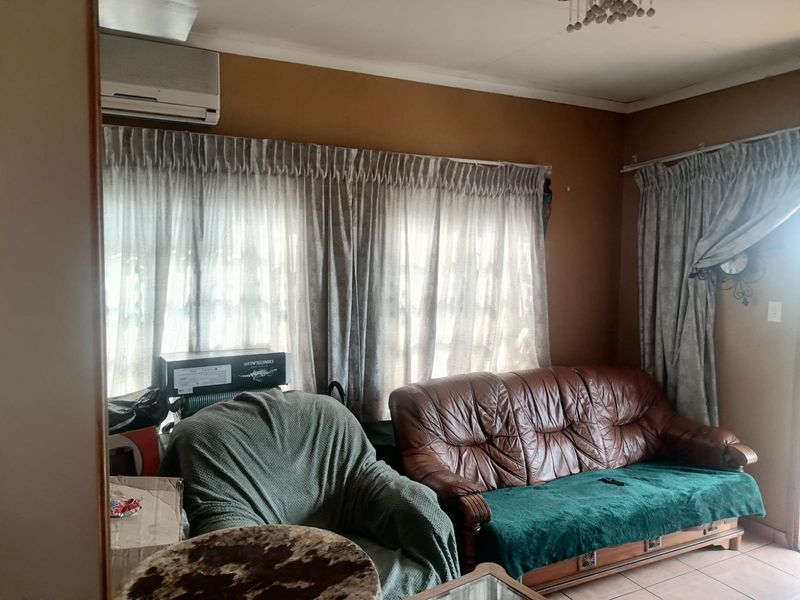 A living room featuring tiled flooring and a wall-mounted split-system air conditioner, offering a functional space with potential for cosmetic updates.