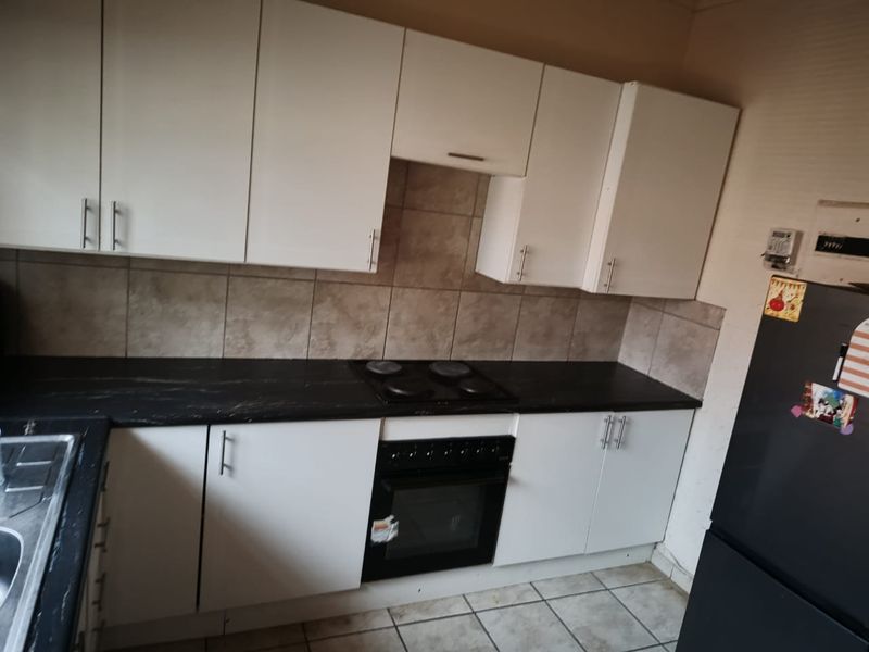 Functional kitchen featuring white cabinetry, dark laminate countertops, built-in oven and hob, tiled backsplash, and tiled flooring.