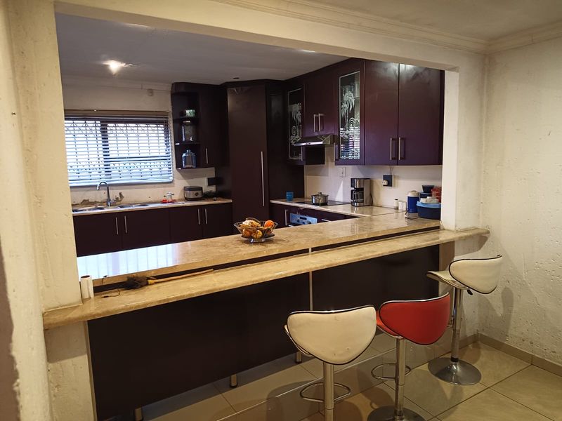 A functional kitchen featuring dark cabinetry, stone countertops, a breakfast bar, and integrated appliances, offering a practical layout for daily cooking and dining.