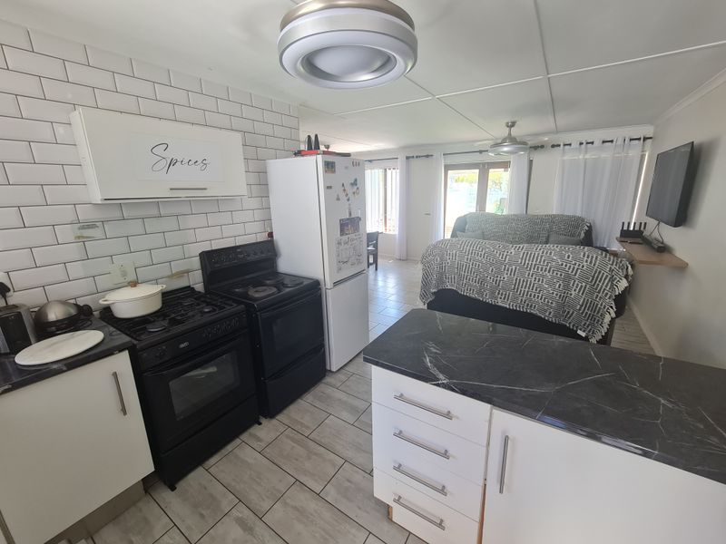 Open-plan kitchen and living area featuring a subway tile backsplash, gas stove, kitchen island, and direct access to the outdoor space.