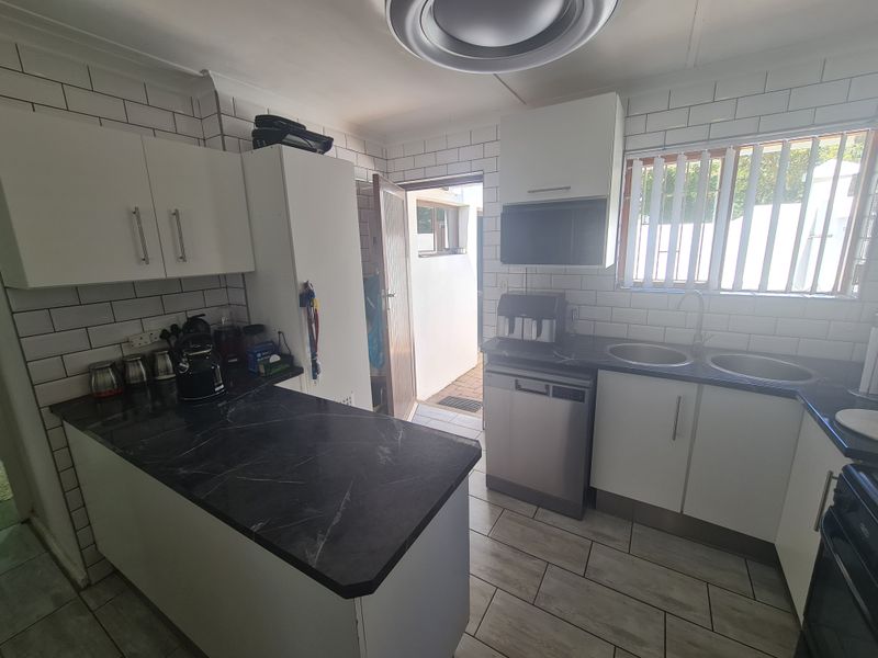 Functional kitchen featuring white cabinetry, subway tile backsplash, dark laminate countertops, and direct access to an outdoor area.