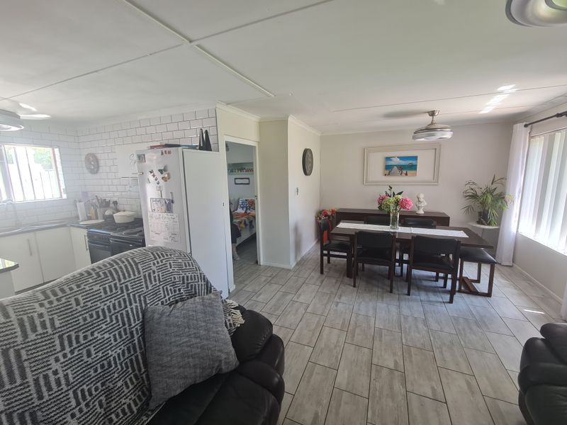 Open plan living and dining area featuring tiled flooring, a modern subway tile kitchen backsplash, and a ceiling fan.