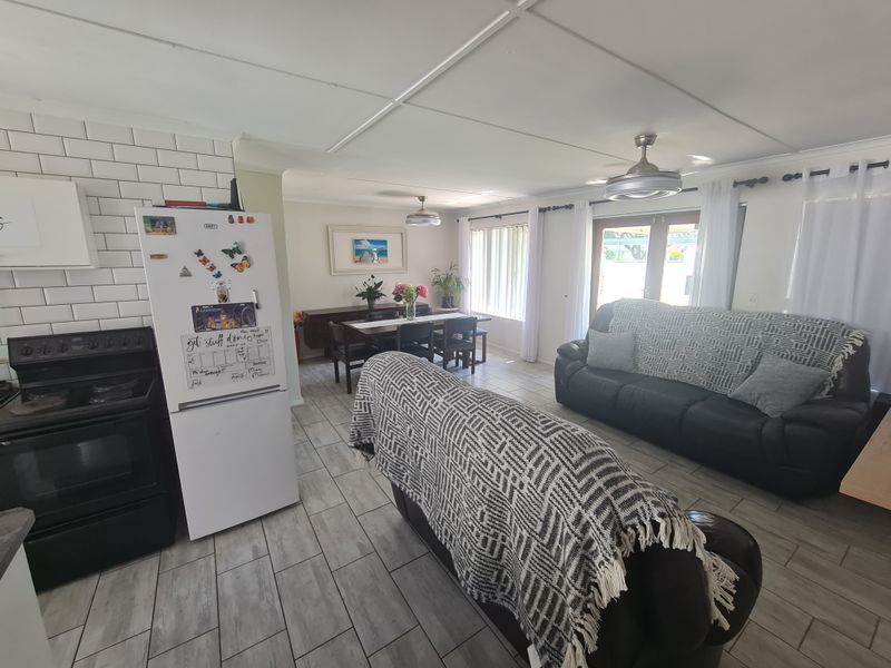 Open-plan living and kitchen area featuring tiled flooring, subway tile backsplash, built-in oven, and direct access to the outdoors through french doors.