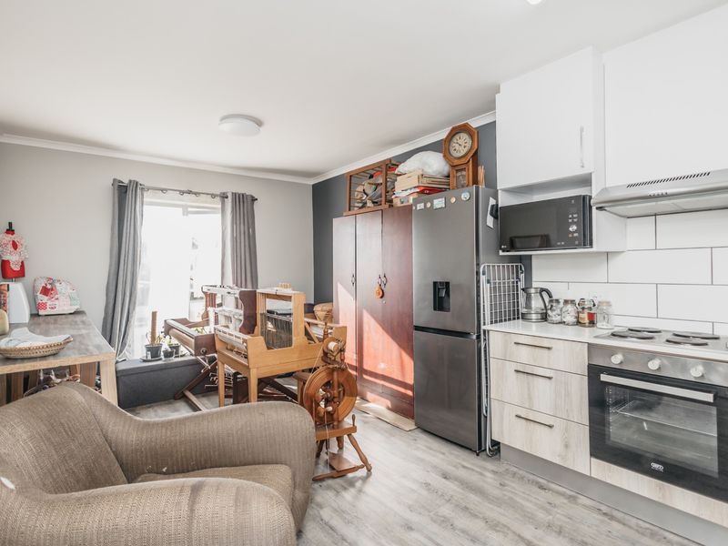 Open-plan living area featuring a modern kitchen with built-in oven, hob, extractor fan, and light-toned cabinetry, seamlessly integrated with the living space.